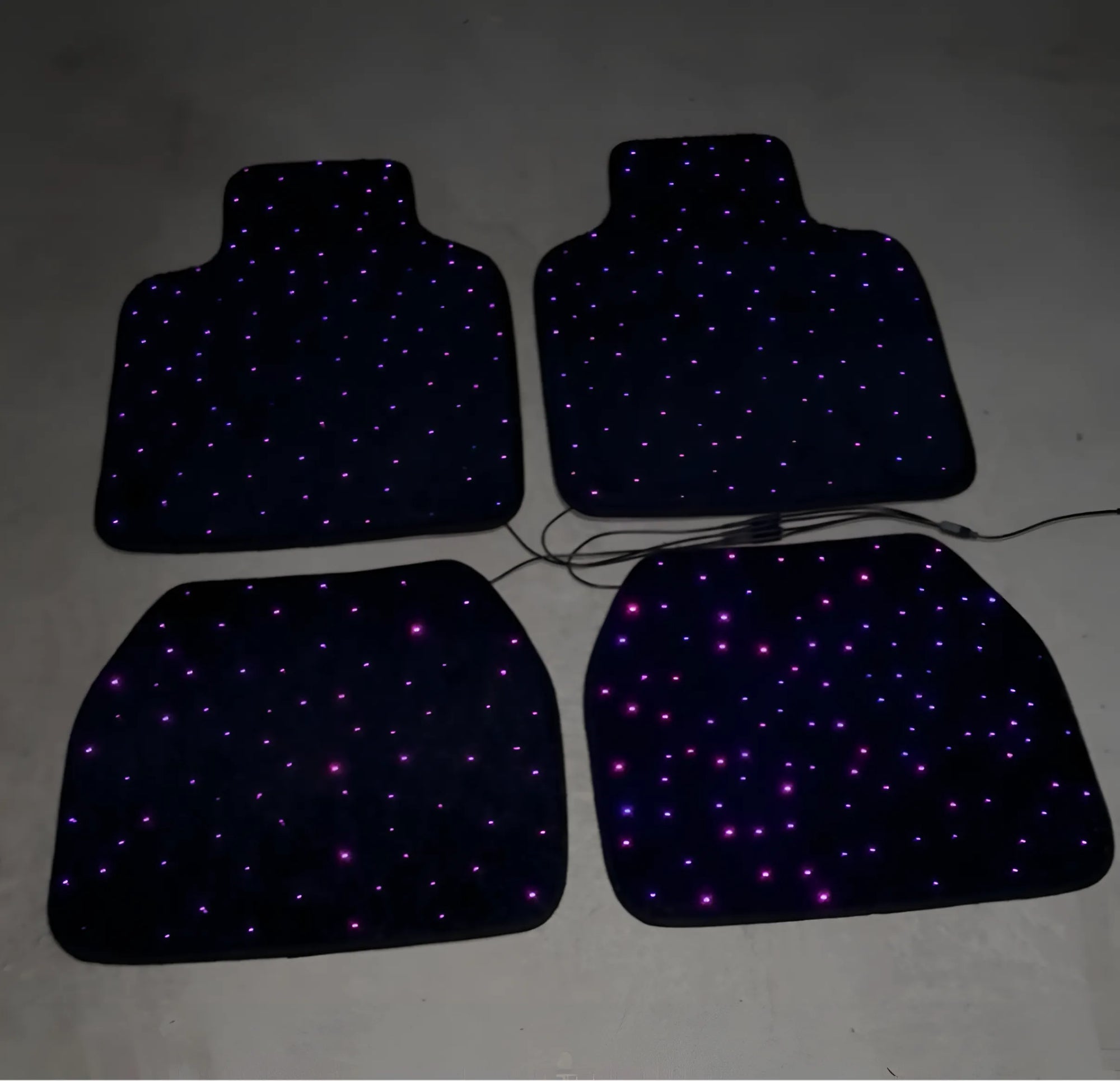Quatro tapetes de carro com LED roxa ligada, mostrando design e iluminação fora do carro